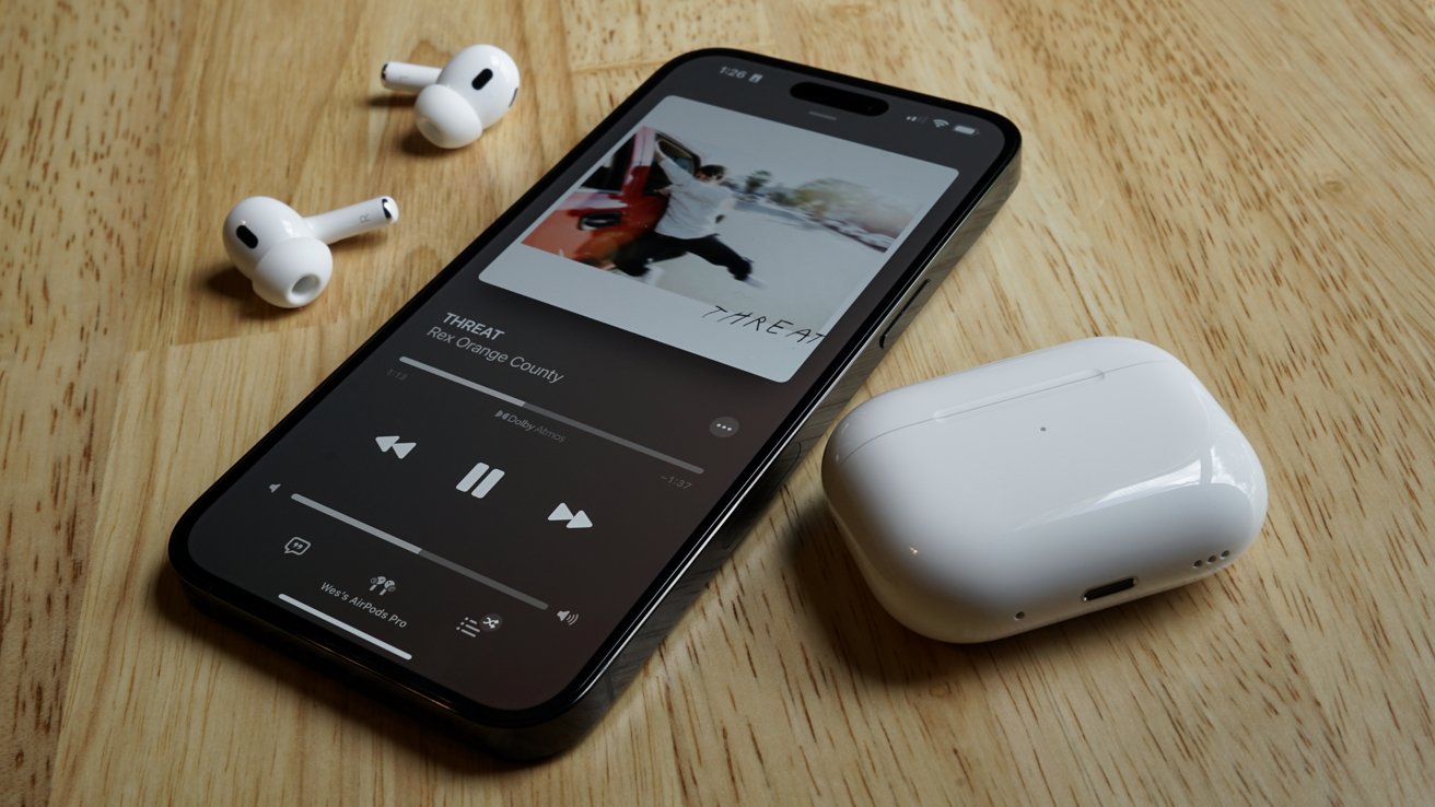 AirPods Pro and their charging case laying next to an iPhone on a desk