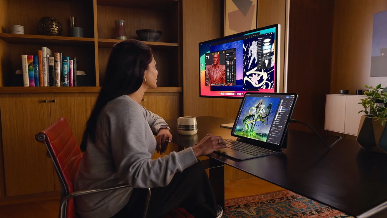 A person uses an iPad Pro in a Magic Keyboard connected to an external display