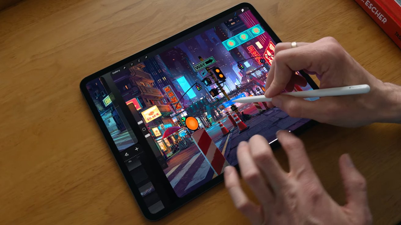 A hand holding the Apple Pencil works on an iPad Pro