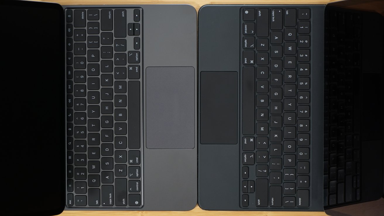 Two laptop keyboards side by side with touchpads placed directly below each keyboard, placed on a wooden surface.