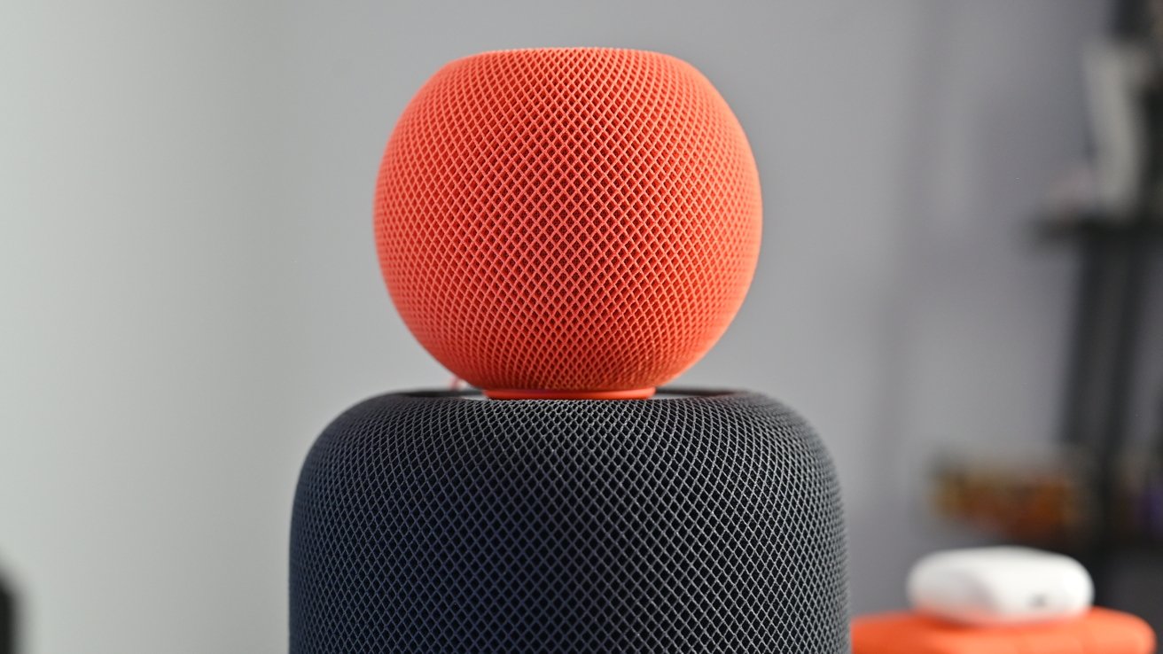 An orange HomePod mini on top of a larger HomePod