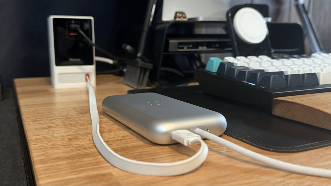 Apple Vision Pro battery on a desk plugged into a charger