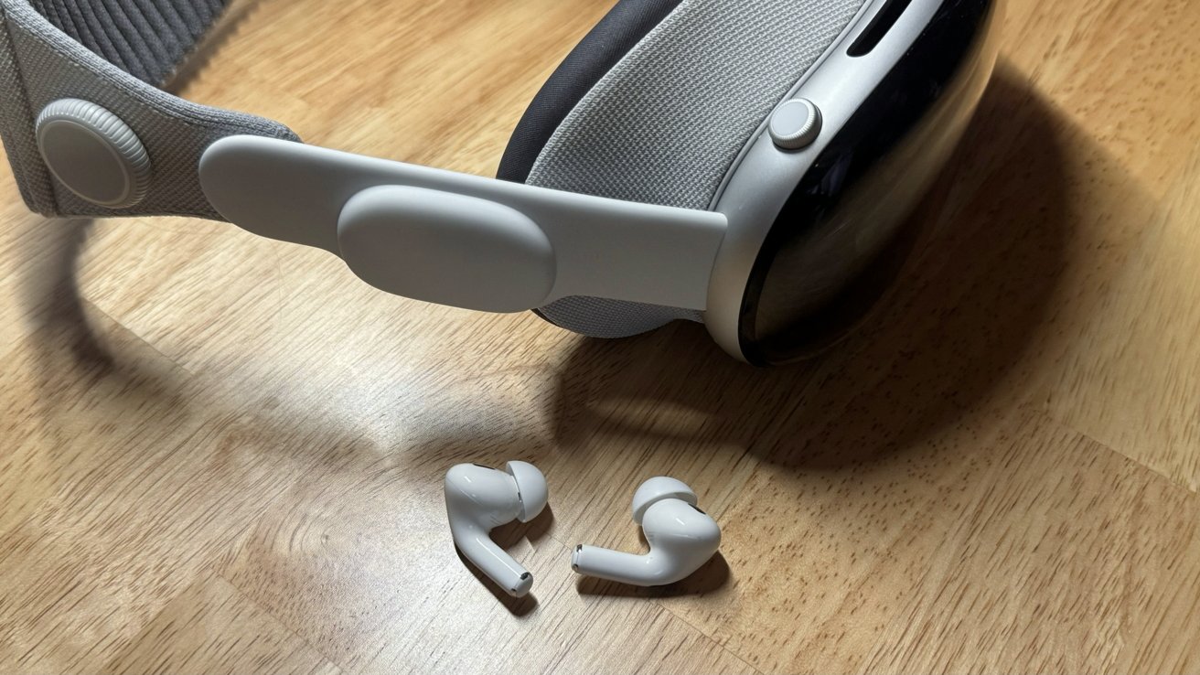 AirPods Pro 2 lay next to Apple Vision Pro on a desk