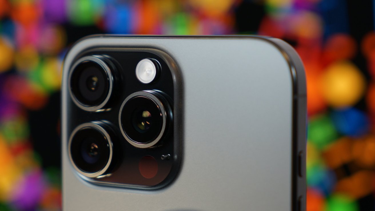 Close-up of a smartphone's three-camera setup with flash against a vibrant, blurred multicolored background.