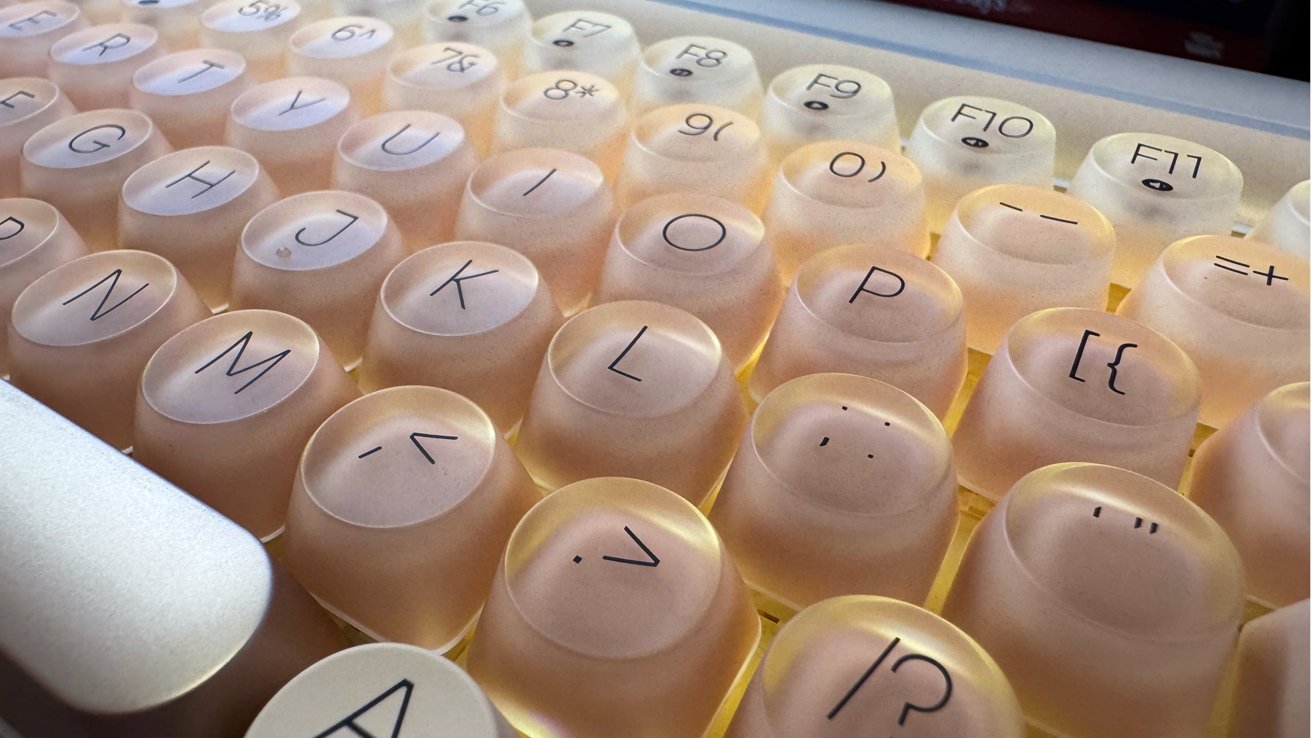 Close-up of pastel-colored translucent keyboard keys with rounded tops and black characters, illuminated from beneath.