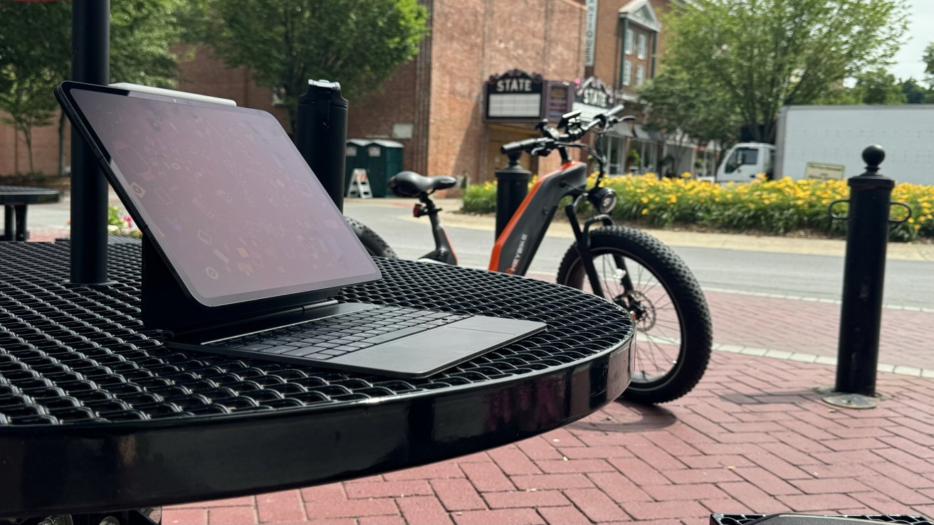 iPad Pro on a table outdoors with an e-bike in the background. The location is in a downtown area.