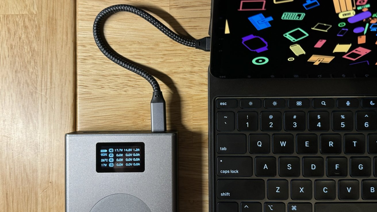 An external battery with a readout of charging speeds connected to the iPad Pro Magic Keyboard