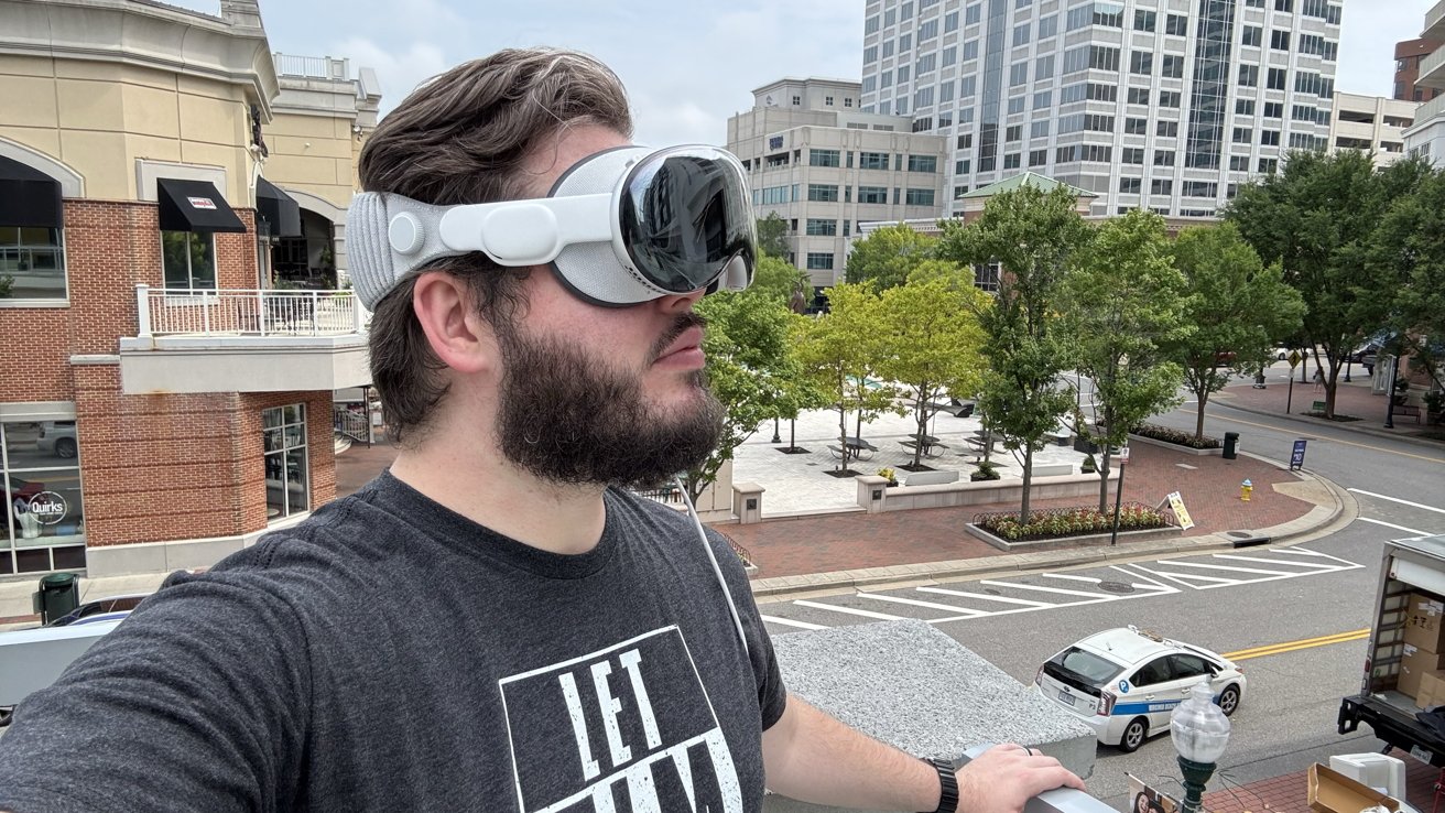 Wesley wearing the Apple Vision Pro on a balcony overlooking a small city square