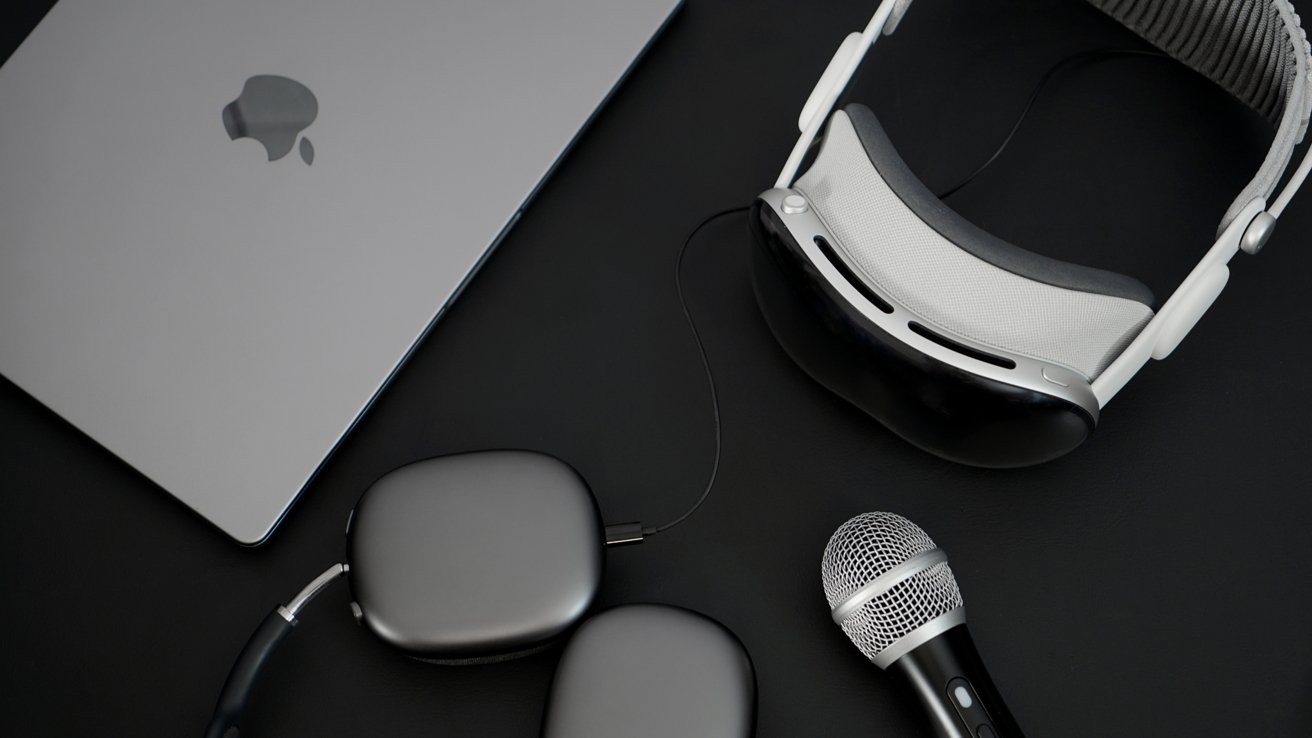 Apple Vision Pro next to a MacBook Pro and a microphone on a dark table