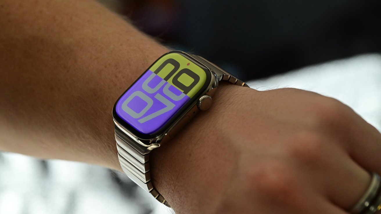 A smartwatch on a wrist displays the time with large numbers on a colorful background, featuring a metal strap.