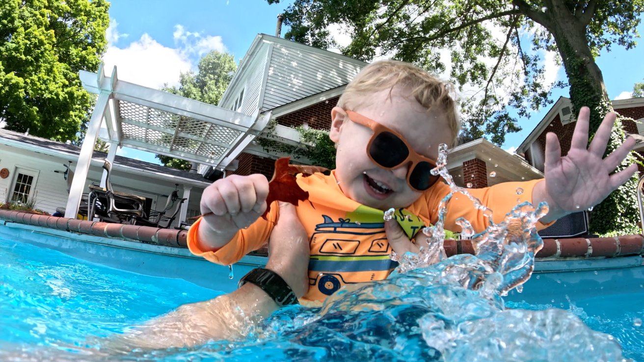 Still frame using burst slow-mo of a toddler jumping into the pool and water frozen in the air