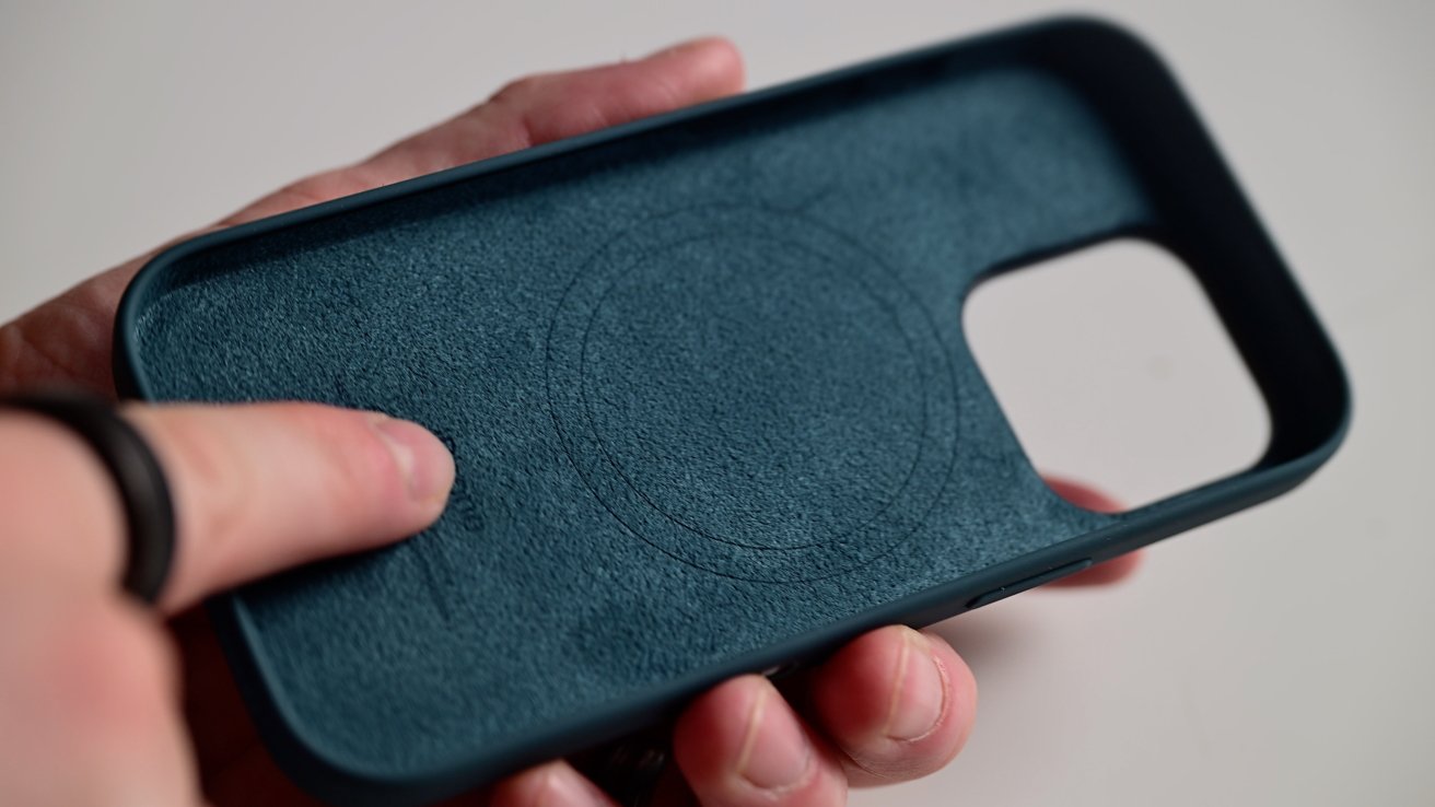 Holding a dark green iPhone case showing the soft microfiber lining