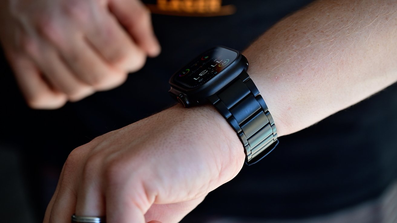 A person wearing a black Apple Watch Ultra with a black metal link band