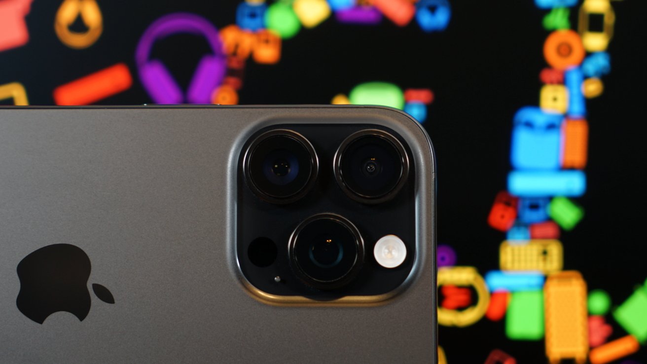 Close-up of a smartphone with three camera lenses, large black Apple logo, and colorful, blurred shapes in the background.