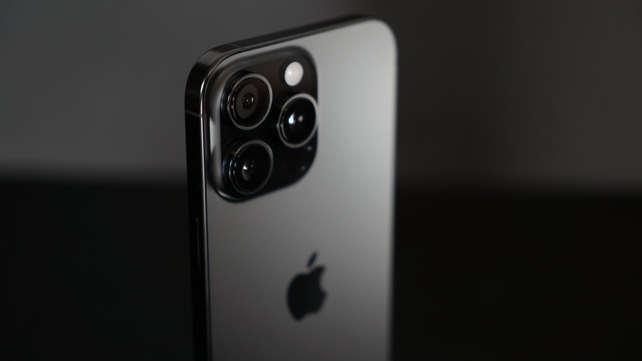 Close-up of a modern smartphone with multiple rear cameras and an Apple logo, set against a dark background.