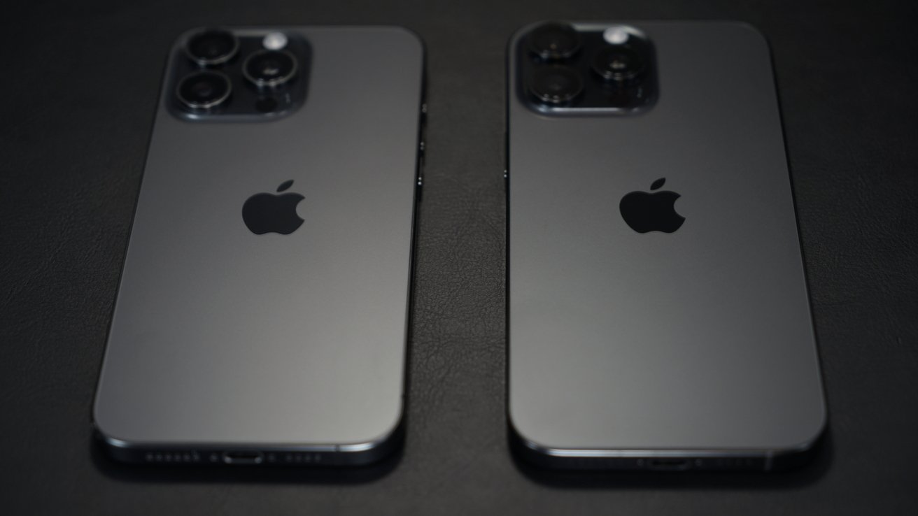 Two black smartphones with the Apple logo, displaying triple and dual camera setups, resting on a dark surface.