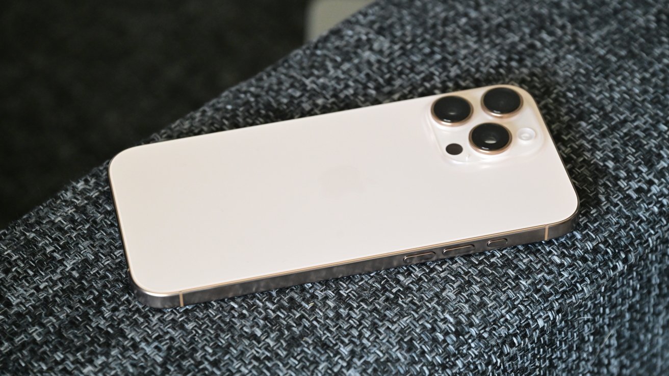 The desert titanium iPhone 16 Pro Max on a couch armrest