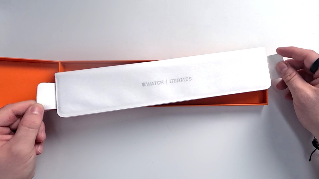 A paper sleeve with the Hermes logo on top that holds the Apple Watch band