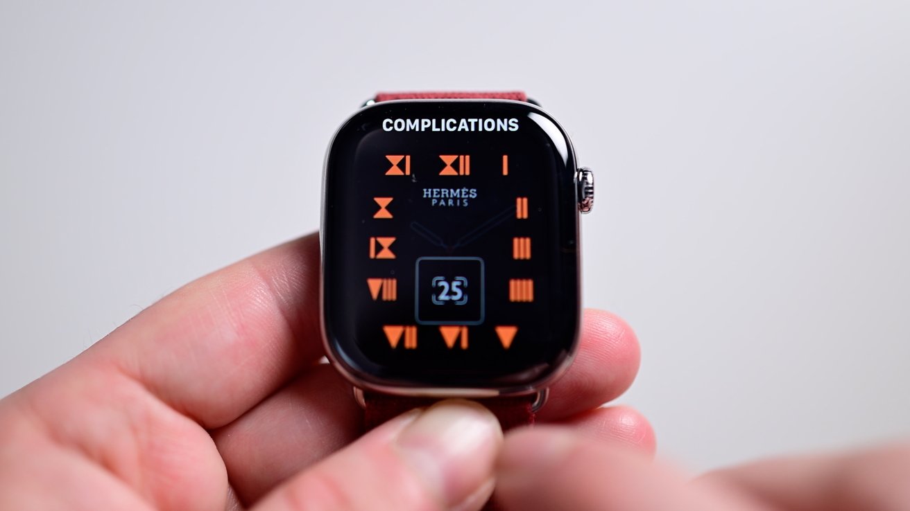 The here's watch face with orange roman numerals around the edge