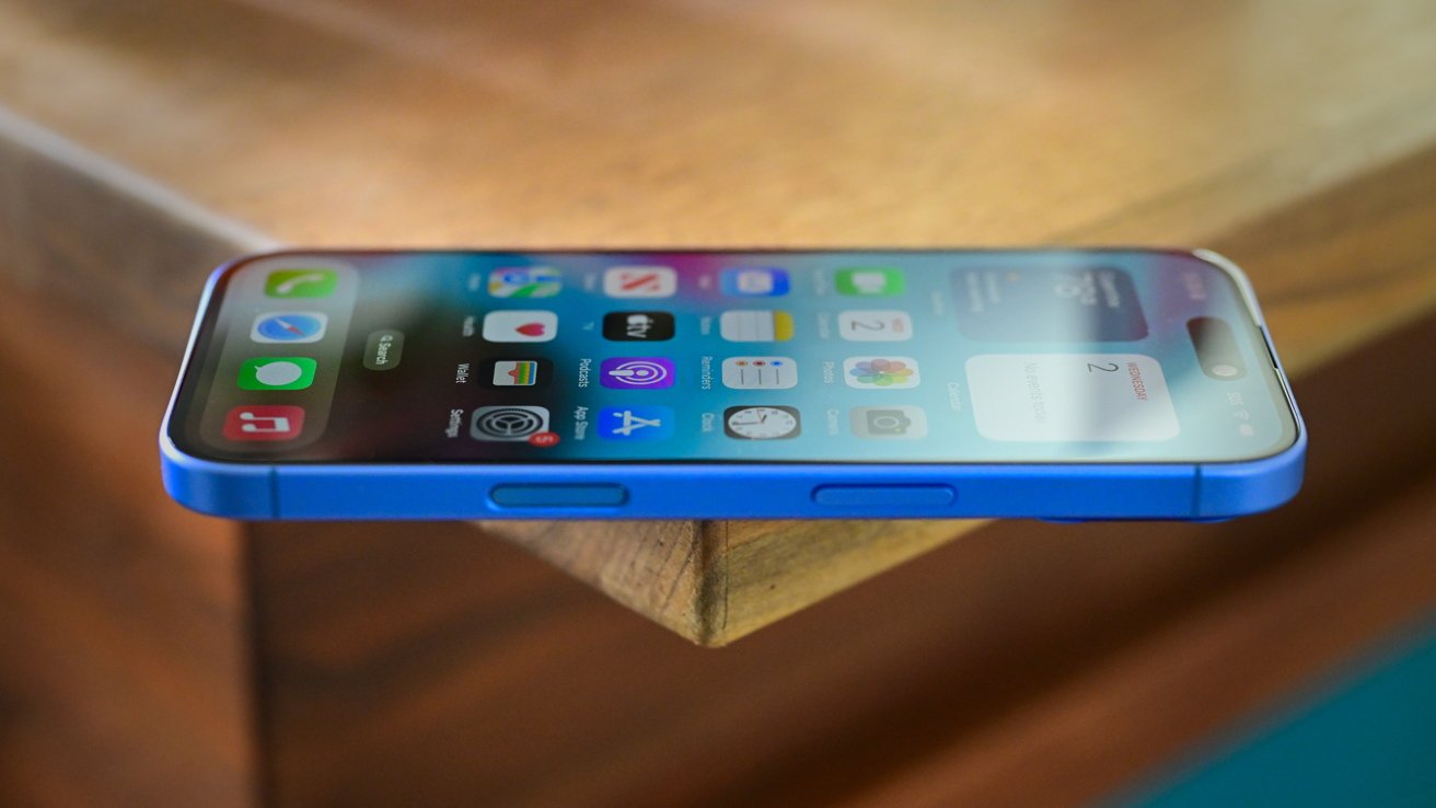 Smartphone with a blue case, displaying app icons, placed on the edge of a wooden table.