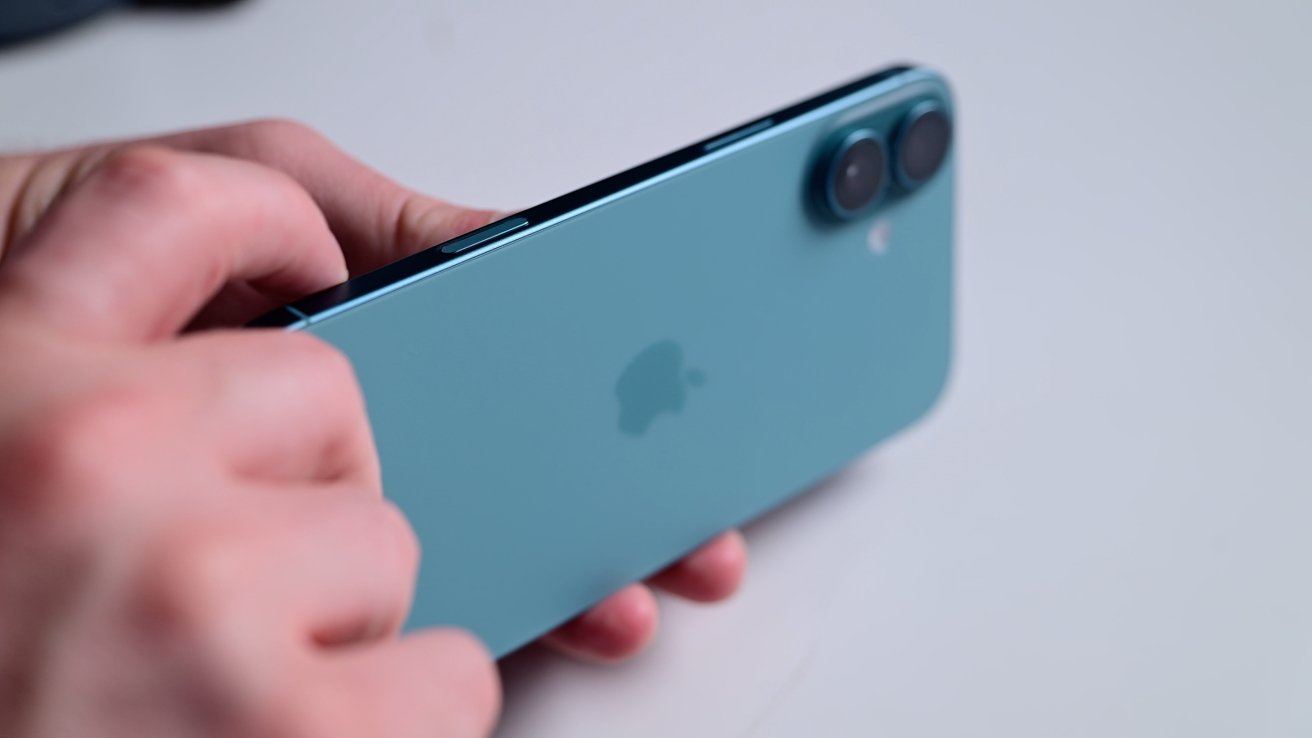 A person holding a blue smartphone with a dual-camera setup and an Apple logo on the back.