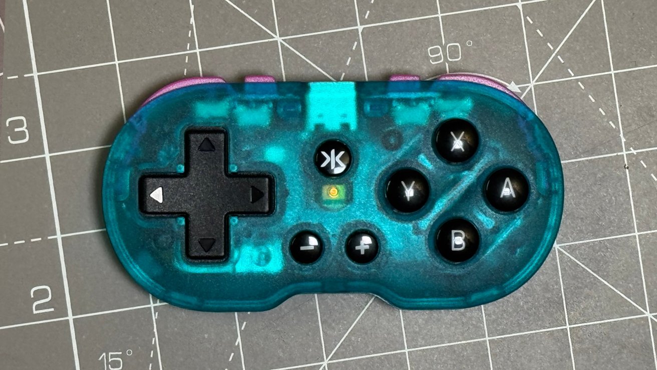 Translucent turquoise game controller with directional pad, buttons labeled X, Y, A, B, plus other symbols, on a gray grid surface.