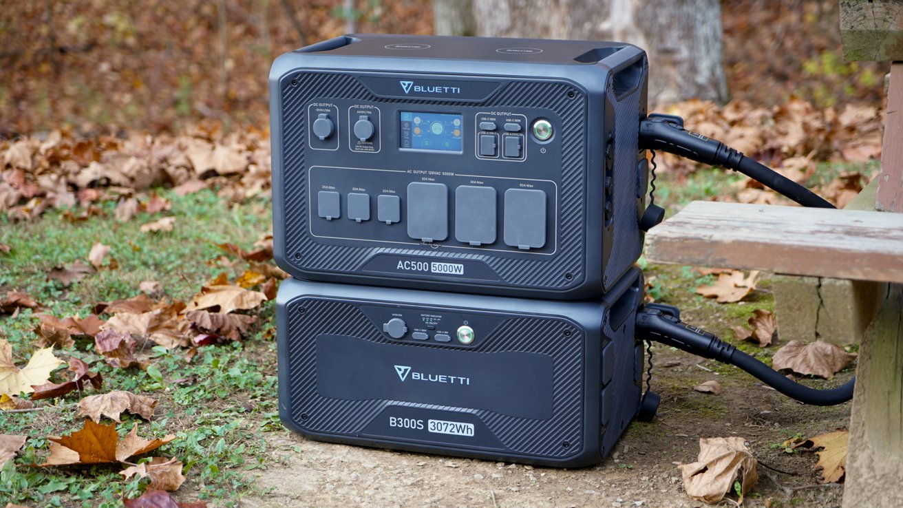 Two stacked portable power stations connected with cables outdoors, surrounded by fallen autumn leaves.