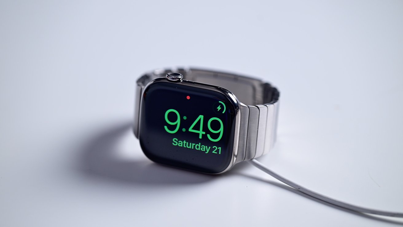 A watch on its charger, sitting on its side showing the time and charging status