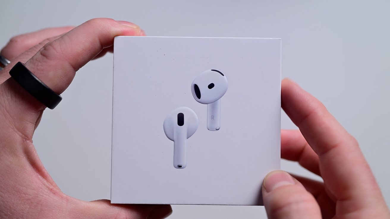 Hands holding a white box with an illustration of white wireless earbuds on the front.