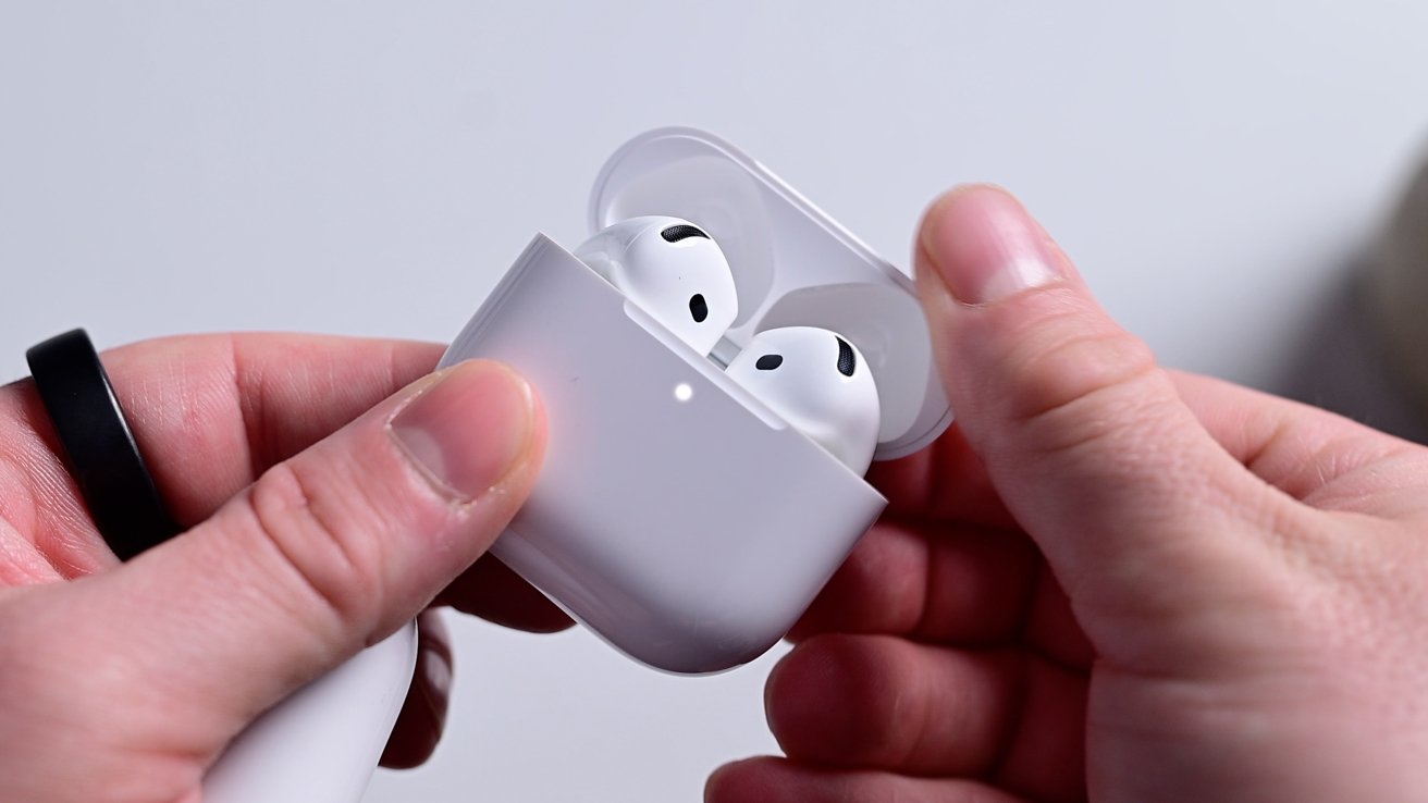 Hands hold open a white charging case containing wireless earbuds.