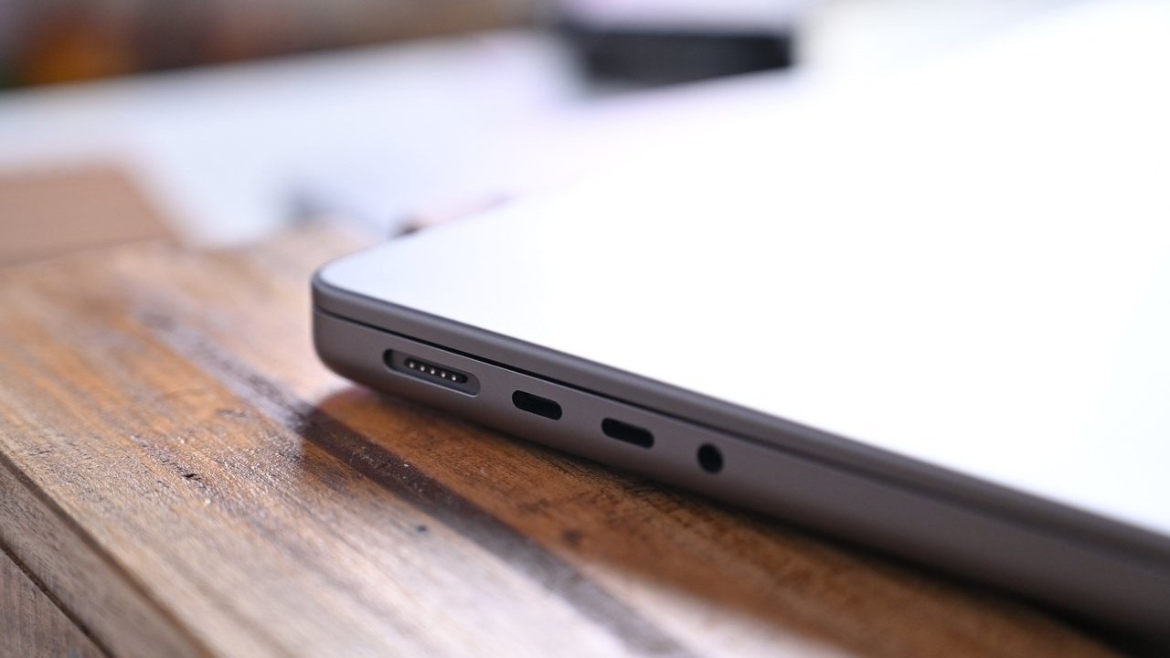 Close-up of a laptop's side, showing multiple ports on a wooden surface.