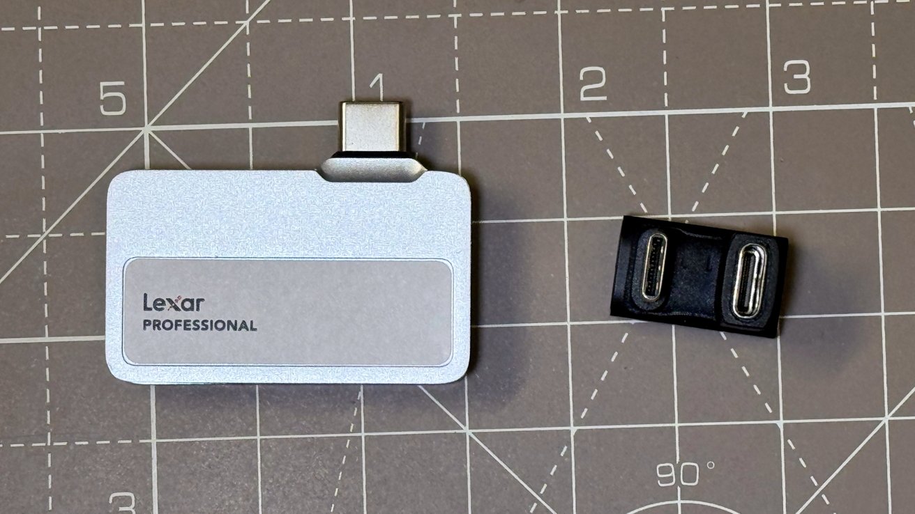 Silver Lexar Professional card reader and black USB-C adapter on a gray cutting mat with grid lines.