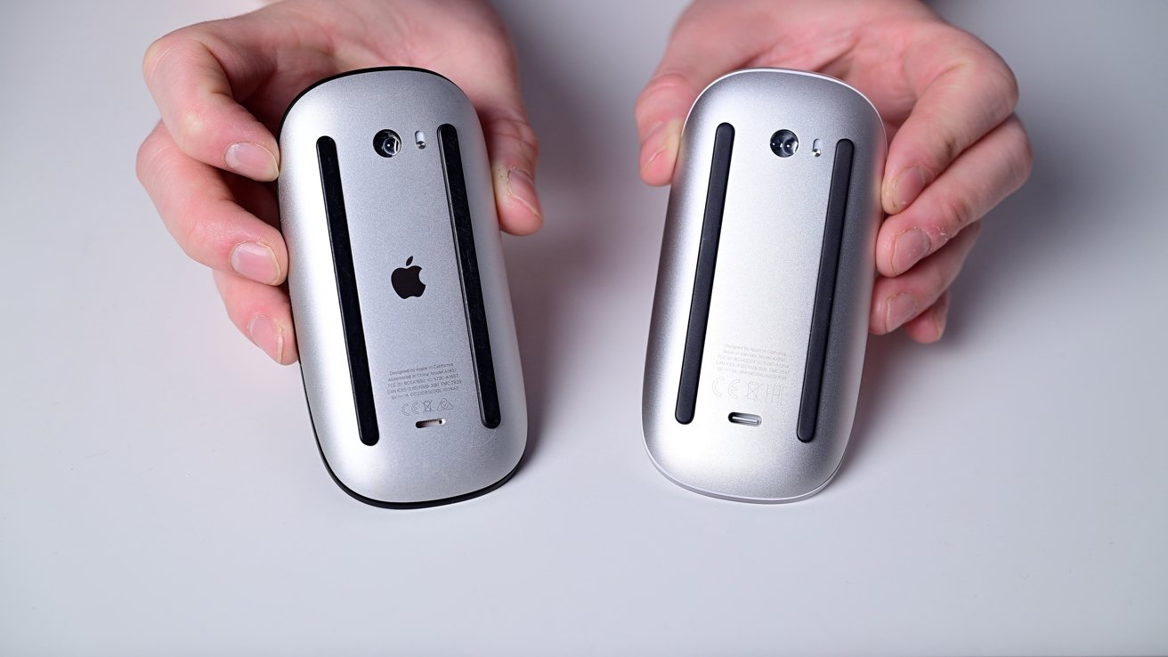 Two hands holding the undersides of two silver computer mice with black stripes and an Apple logo.