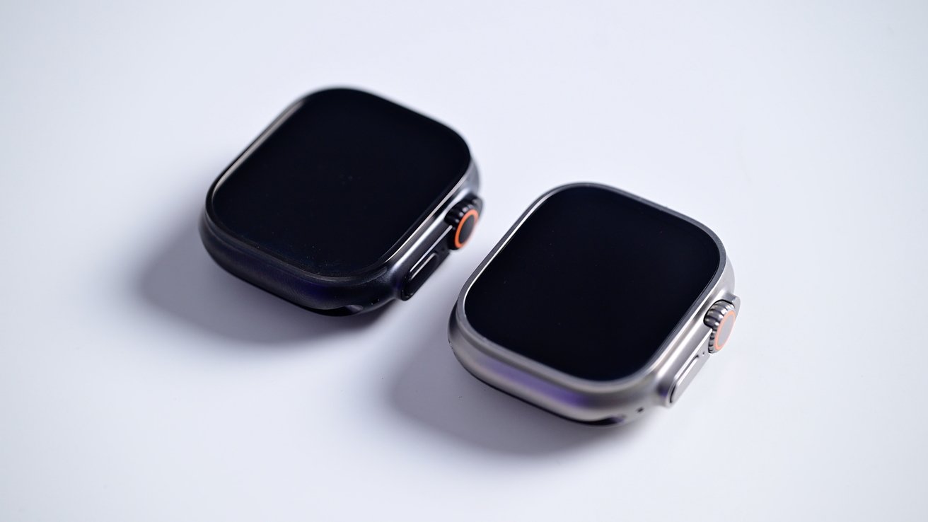 A hand holds a dark smartwatch with an orange-accented button and a braided strap against a blurred background.