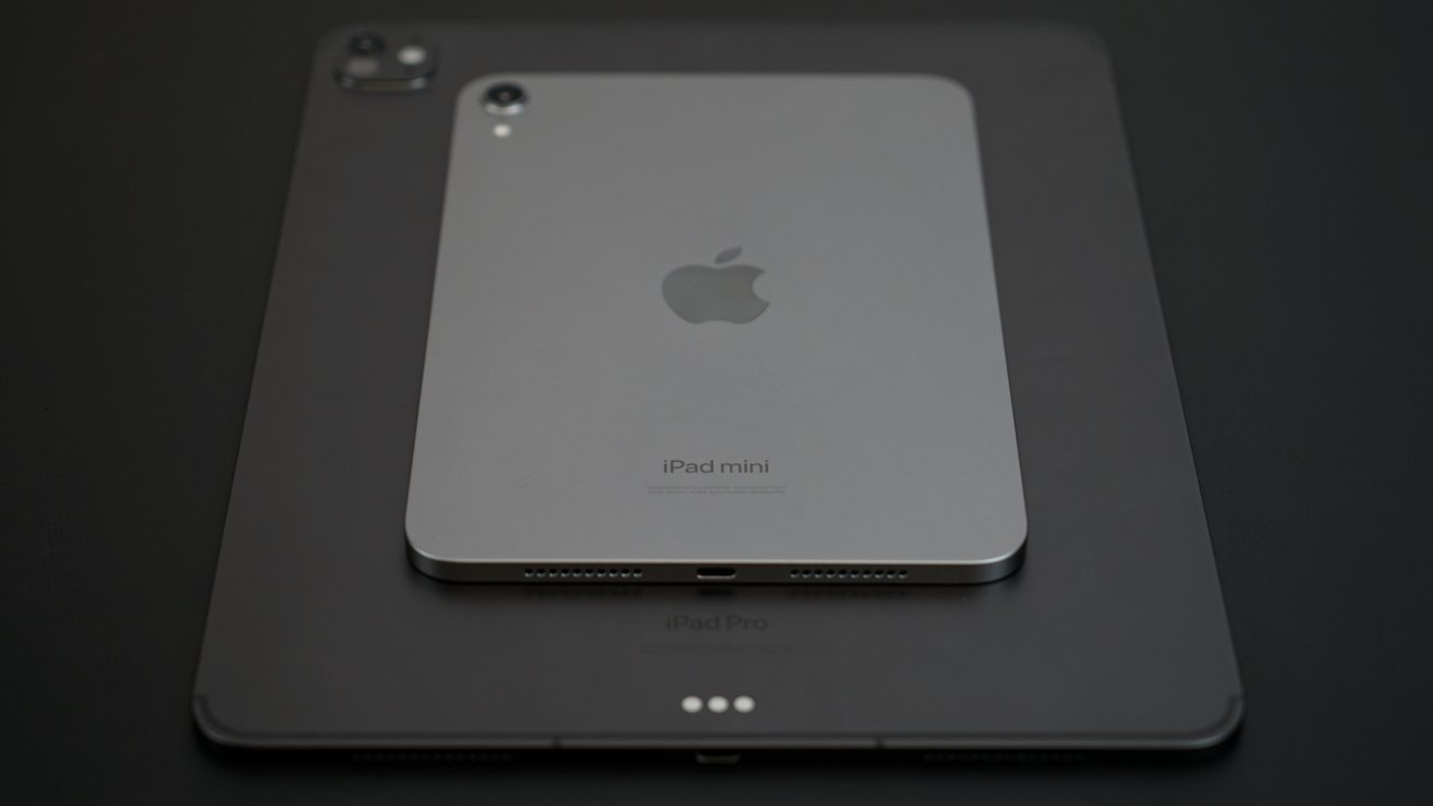 Two Apple devices stacked; an iPad mini resting on a larger iPad Pro, both in a dark, minimalist setting.