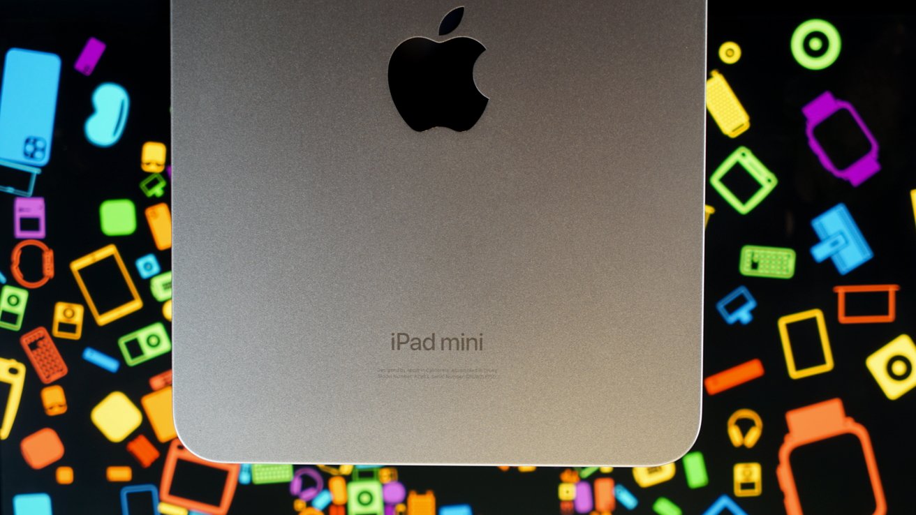 Silver iPad Mini with Apple logo against a colorful background of various digital and tech-related icons.