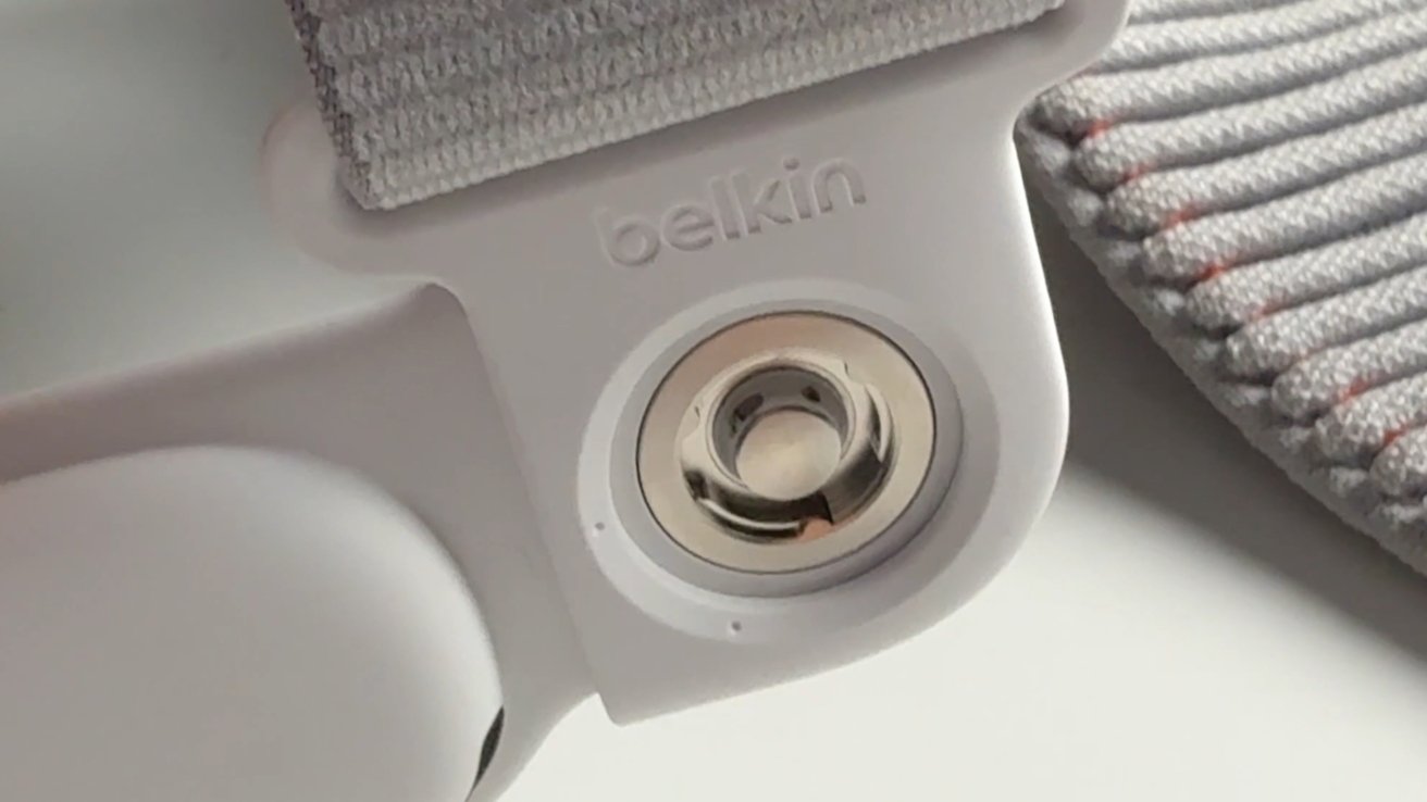 Close-up of a gray and white fabric strap with a metal button and 'belkin' logo, alongside patterned stitching detail.