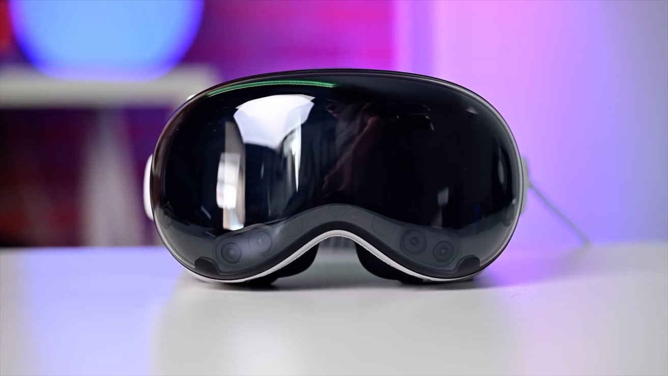 A sleek, reflective virtual reality headset on a white surface with a softly blurred, colorful background.