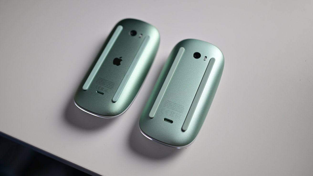 Two metallic green computer mice with smooth surfaces and black logos on a light gray background.