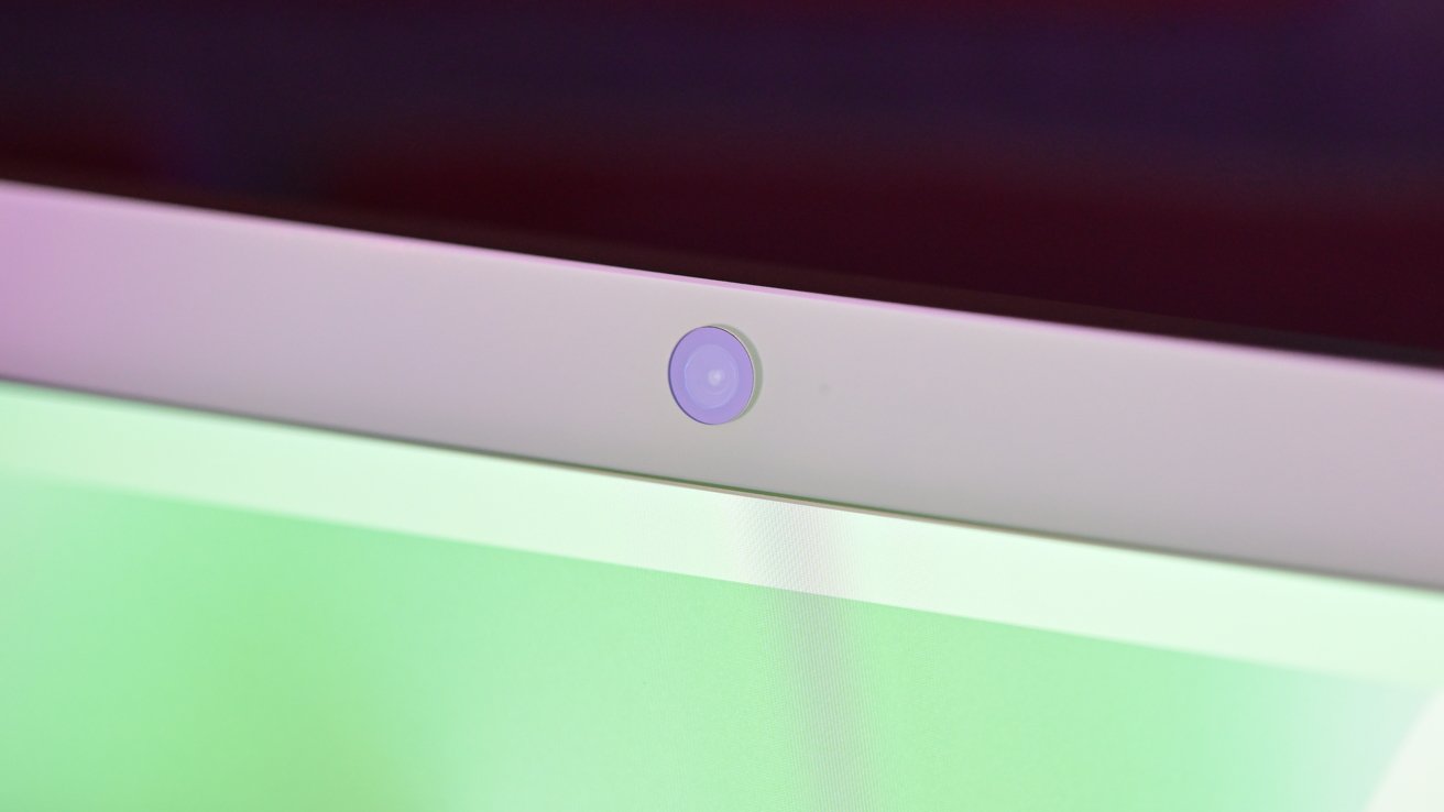 Webcam lens centered on a laptop bezel, with the screen displaying a green hue.