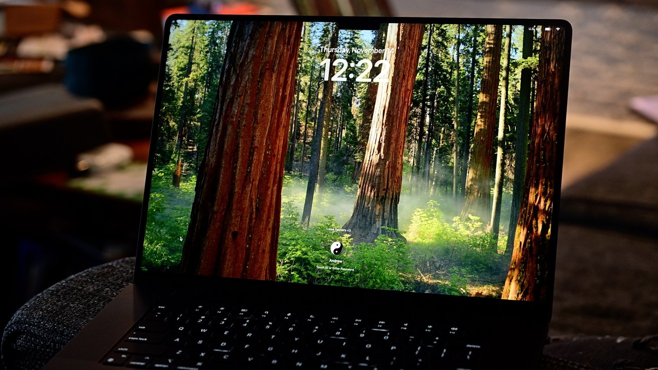 A laptop screen displays a forest with tall trees and mist, showing a time of 12:22 and a login prompt with a yin-yang symbol.