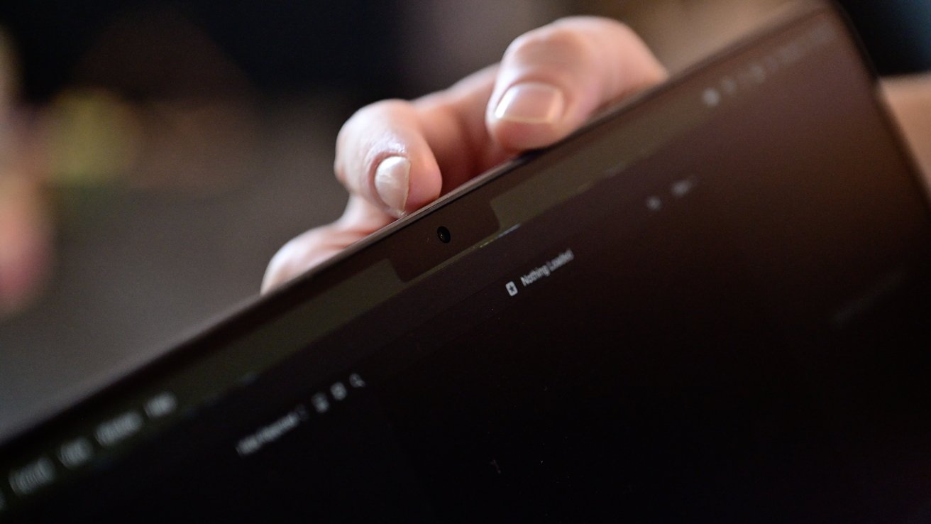 A close-up of a hand adjusting the webcam cover on a laptop screen.