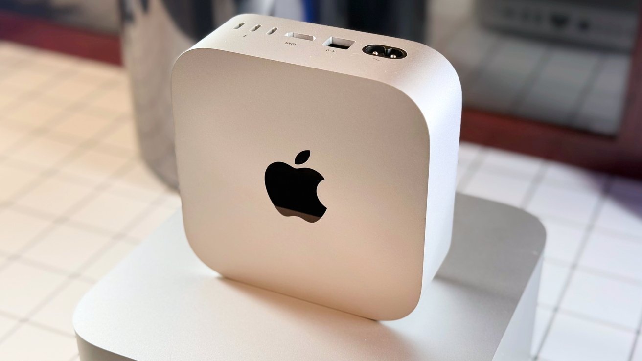 Silver Apple Mac mini M4 computer with the Apple logo on a tiled surface, ports visible on top.