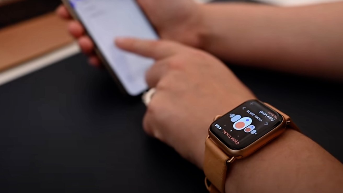 Person using a smartphone while wearing a smartwatch with a leather band, displaying colorful health or activity metrics.