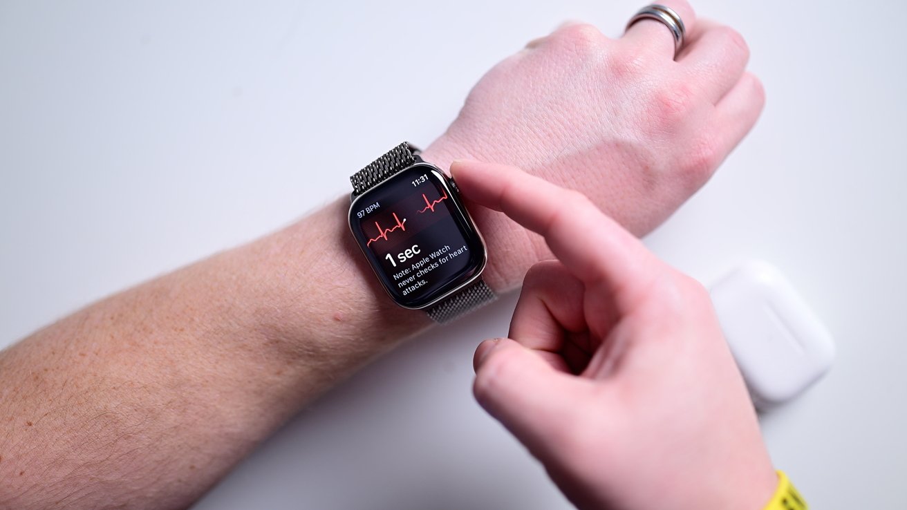 Person's hand wearing a smartwatch displaying heart rate with another hand interacting with it, against a white background.